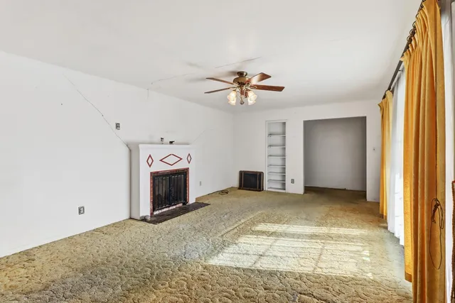 a view of an empty room with a fireplace and a window