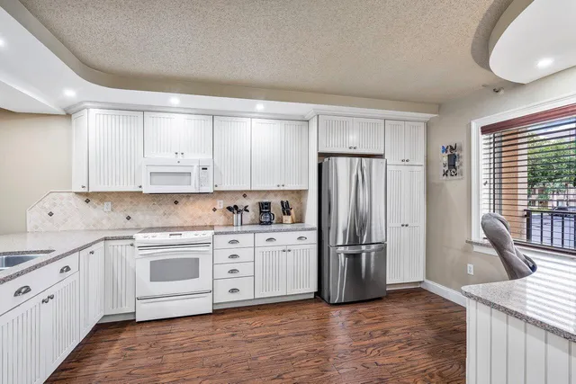 a kitchen with white cabinets sink and dishwasher with wooden floor