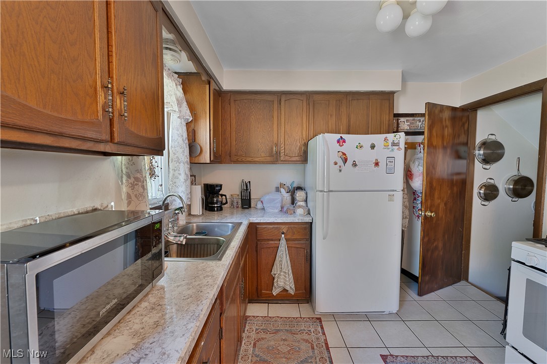 9925 Struthers Road New Middletown, OH 44442 - Photo 6 of 12 Kitchen with white appliances, brown cabinetry, light countertops, and light tile patterned flooring