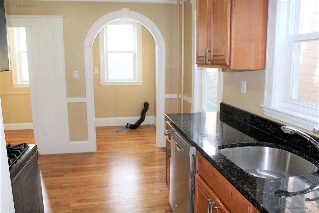 14 Ginita Street, Unit 1 Boston, MA 02122 - Photo 11 of 12 a kitchen with granite countertop a sink a stove and cabinets