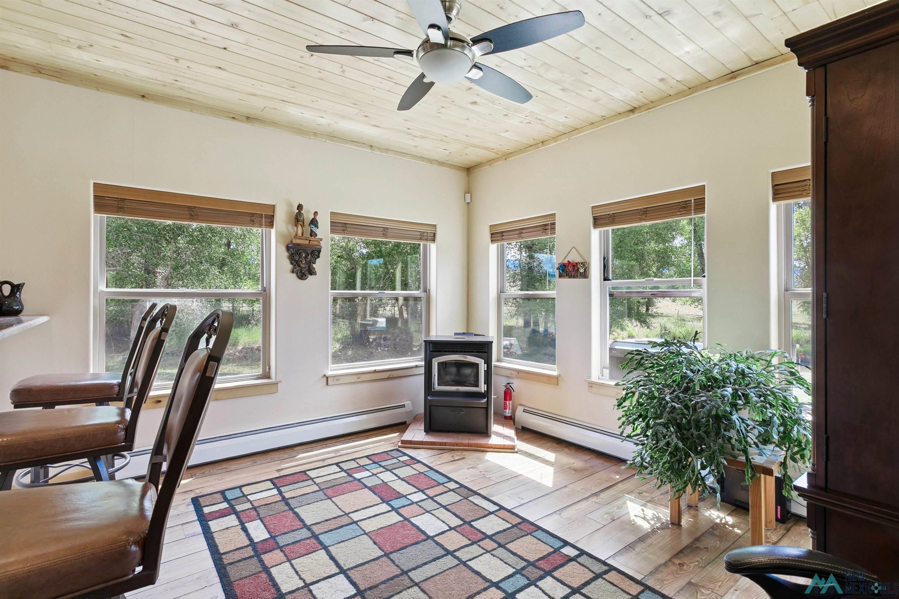 31 Cr 343 Road Chama, NM 87520 - Photo 13 of 44 Office featuring a wood stove, wood ceiling, light wood-style floors, a baseboard heating unit, and a ceiling fan