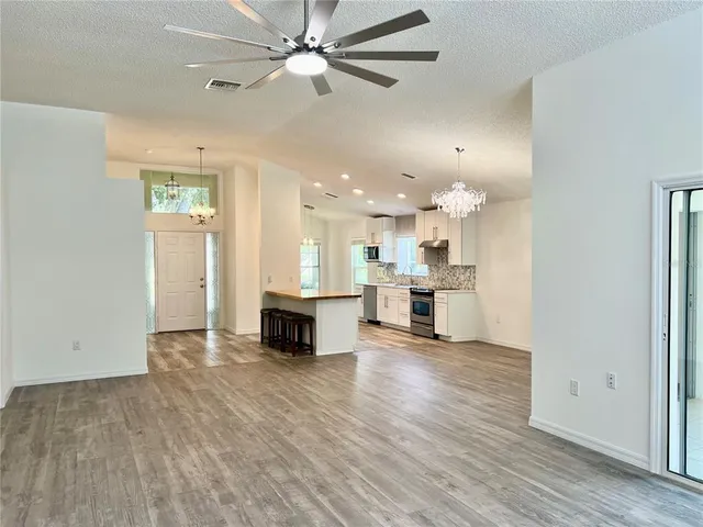 a view of a kitchen with kitchen island wooden floors appliances and a ceiling fan