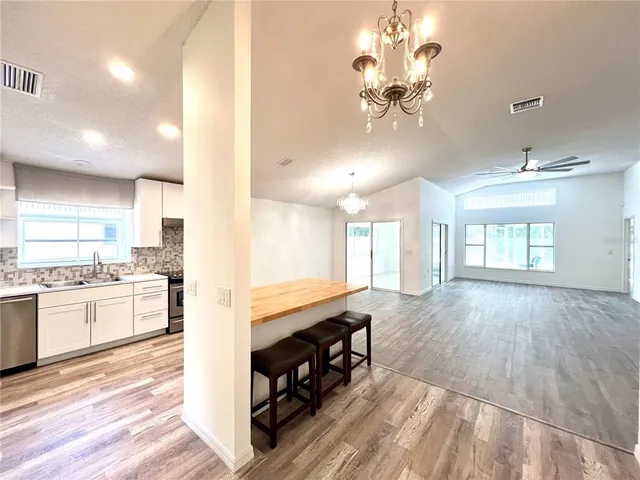 a large kitchen with kitchen island a stove a sink a dining table and chairs with wooden floor