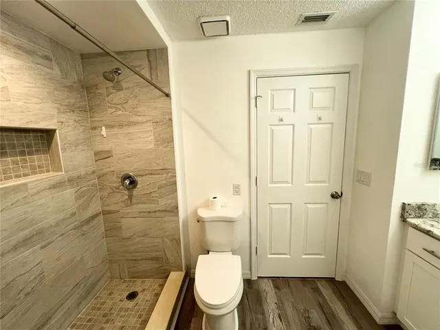 a bathroom with a granite countertop toilet a sink and shower