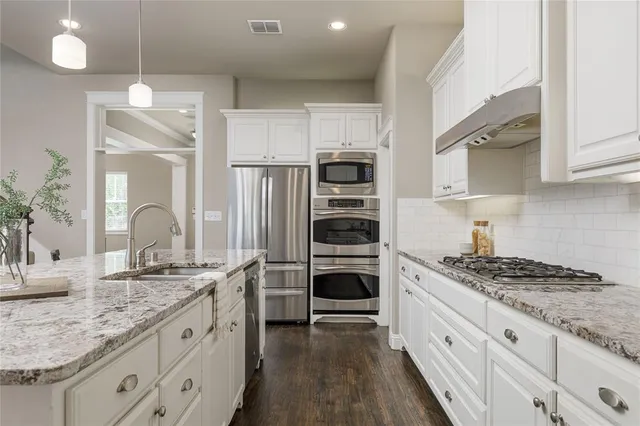 a kitchen with stainless steel appliances granite countertop a dining table chairs refrigerator and microwave