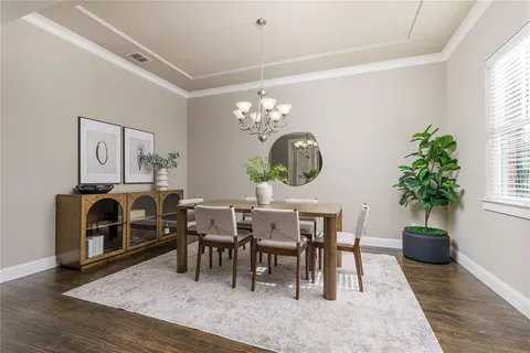 a living room with furniture a dining table a chandelier and a potted plant