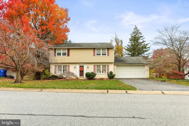 a view of a house with a yard and large tree
