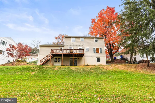 a view of a white house with a big yard and large trees