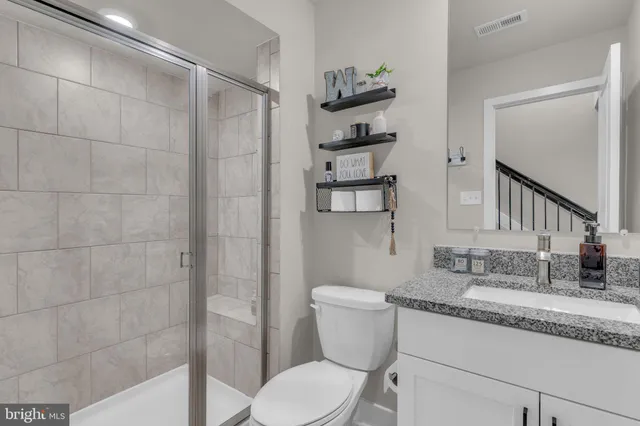 a bathroom with a granite countertop sink toilet and shower