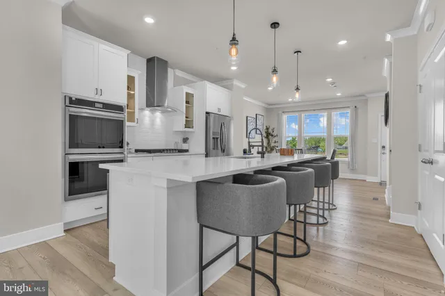 a kitchen with stainless steel appliances kitchen island granite countertop a stove a sink a refrigerator and a dining table with wooden floor