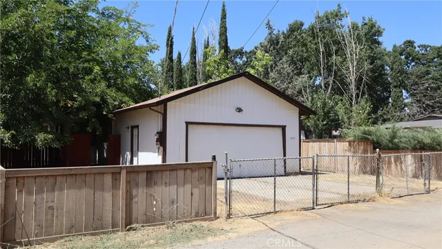 a view of backyard with large tree and wooden fence
