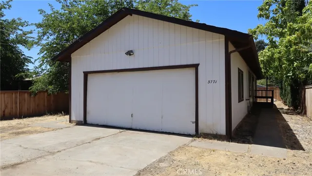 a view of backyard of house with wooden fence and trees