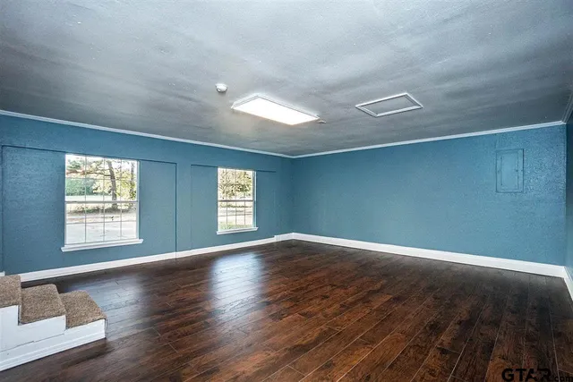 an empty room with wooden floor and windows