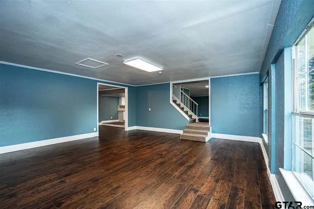 a view of an empty room with wooden floor and stairs