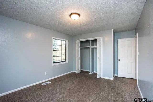 an empty room with closet and windows