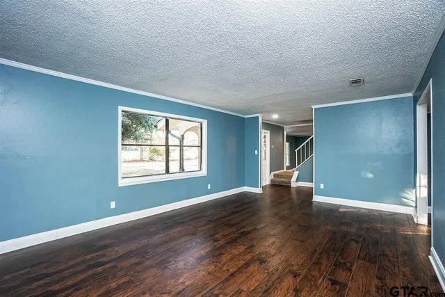 a view of an empty room with window and wooden floor