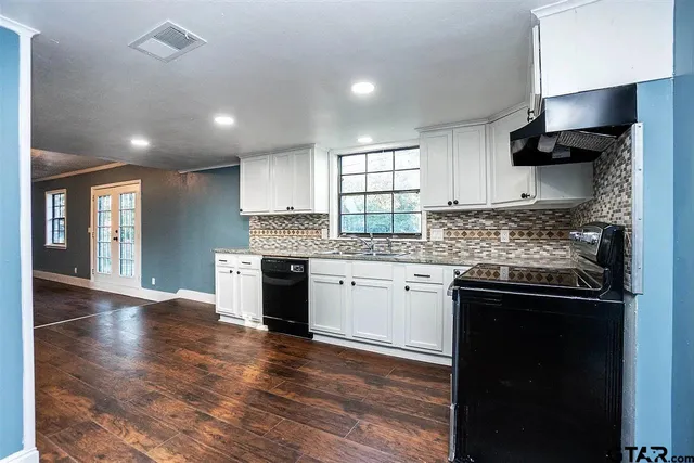 a kitchen with granite countertop a stove top oven a sink dishwasher and a refrigerator with wooden floor