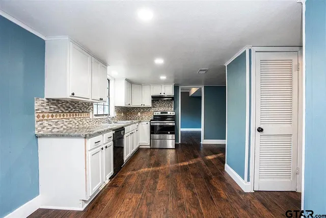 a kitchen with granite countertop a stove top oven and cabinets