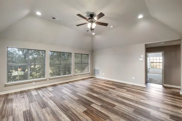 a view of empty room with wooden floor and fan