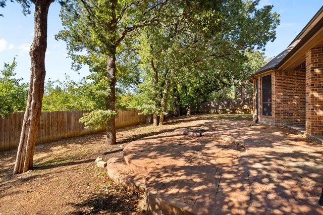a view of a yard with large trees and wooden fence