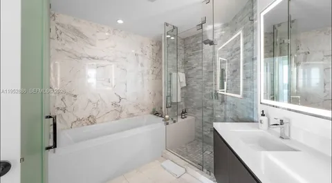 a bathroom with a granite countertop sink a mirror a bathtub and shower