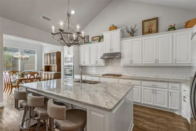 a very nice looking kitchen with granite countertop a table chairs in it
