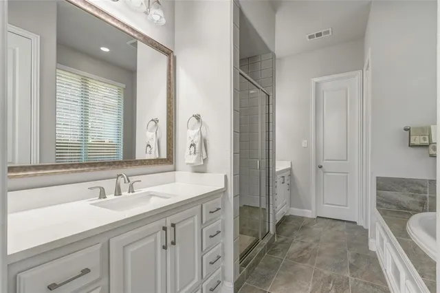 a spacious bathroom with a double vanity sink a mirror and a shower