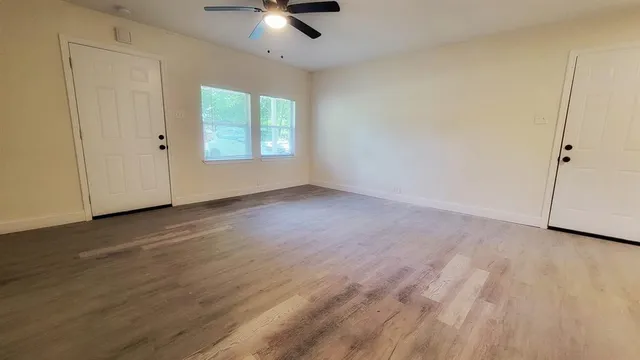an empty room with wooden floor cabinet and windows