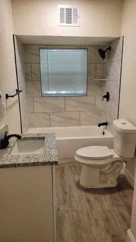 a bathroom with a granite countertop sink mirror vanity and toilet