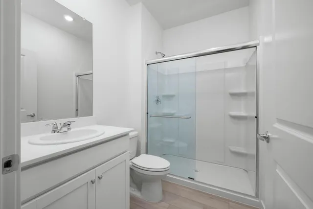 a bathroom with a shower sink vanity mirror and toilet