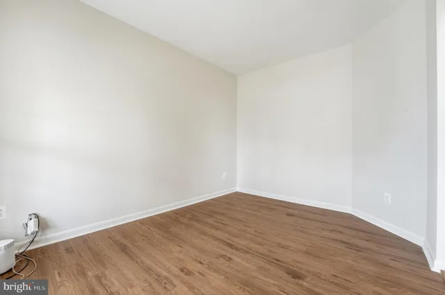 a view of an empty room with chandelier and wooden floor