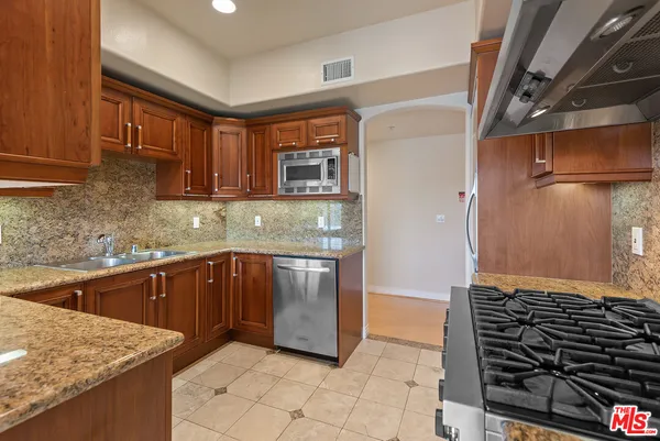 a kitchen with stainless steel appliances granite countertop a stove a sink and a microwave