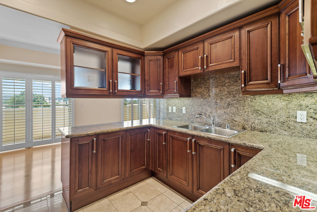 11540 Rochester Avenue, Unit 103 Los Angeles, CA 90025 - Photo 6 of 15 a kitchen with stainless steel appliances granite countertop wooden cabinets a sink and dishwasher