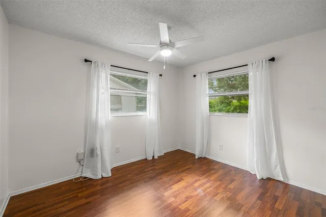 an empty room with wooden floor chandelier and windows