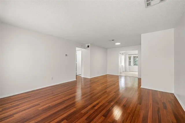 a view of an empty room with wooden floor and window