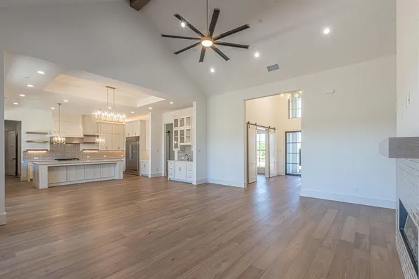 a view of an empty room and kitchen with wooden floor