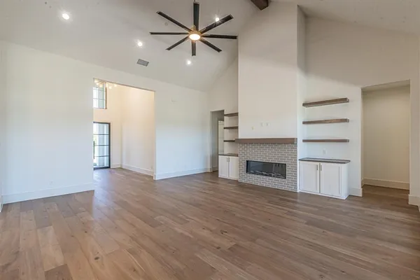 an empty room with wooden floor closet and windows