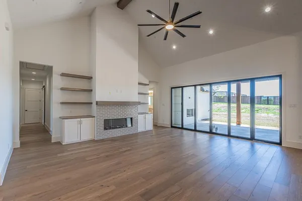 a view of an empty room with a window and wooden floor