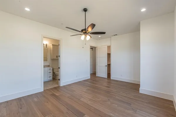 an empty room with wooden floor and a ceiling fan