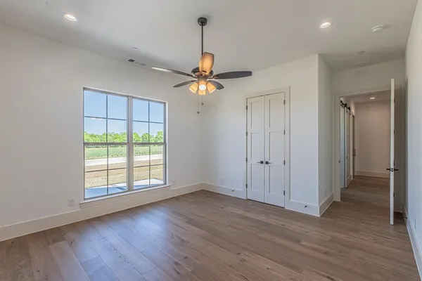 an empty room with wooden floor and ceiling fan