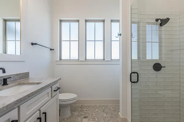 a bathroom with a granite countertop toilet a sink a mirror and shower