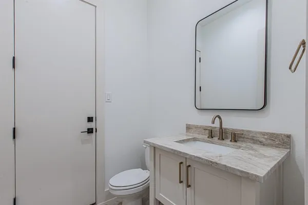 a bathroom with a granite countertop sink toilet and mirror