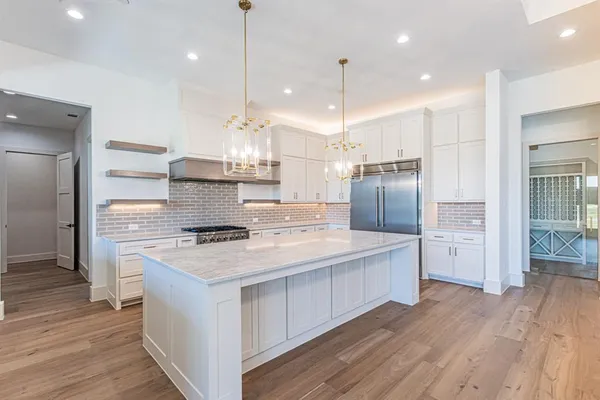 a kitchen with kitchen island a stove a sink a refrigerator and a wooden floor