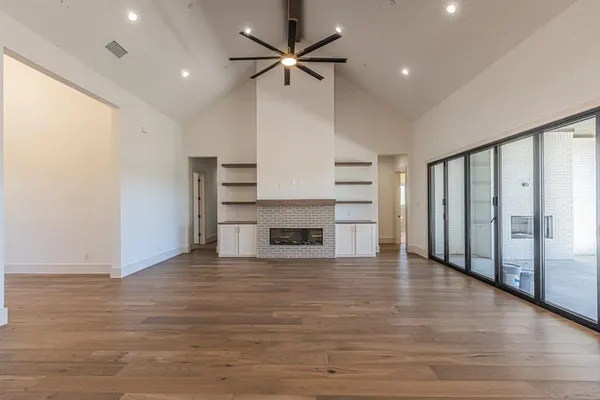 a view of an empty room with a fireplace and a ceiling fan