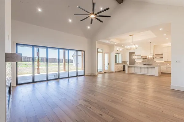 a view of an empty room with wooden floor and a ceiling fan