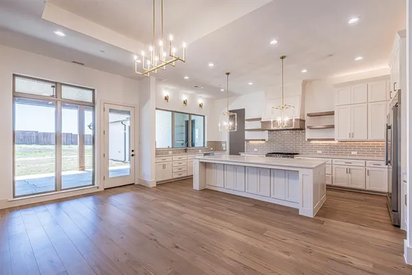 a large kitchen with granite countertop a large counter top a sink stainless steel appliances and cabinets