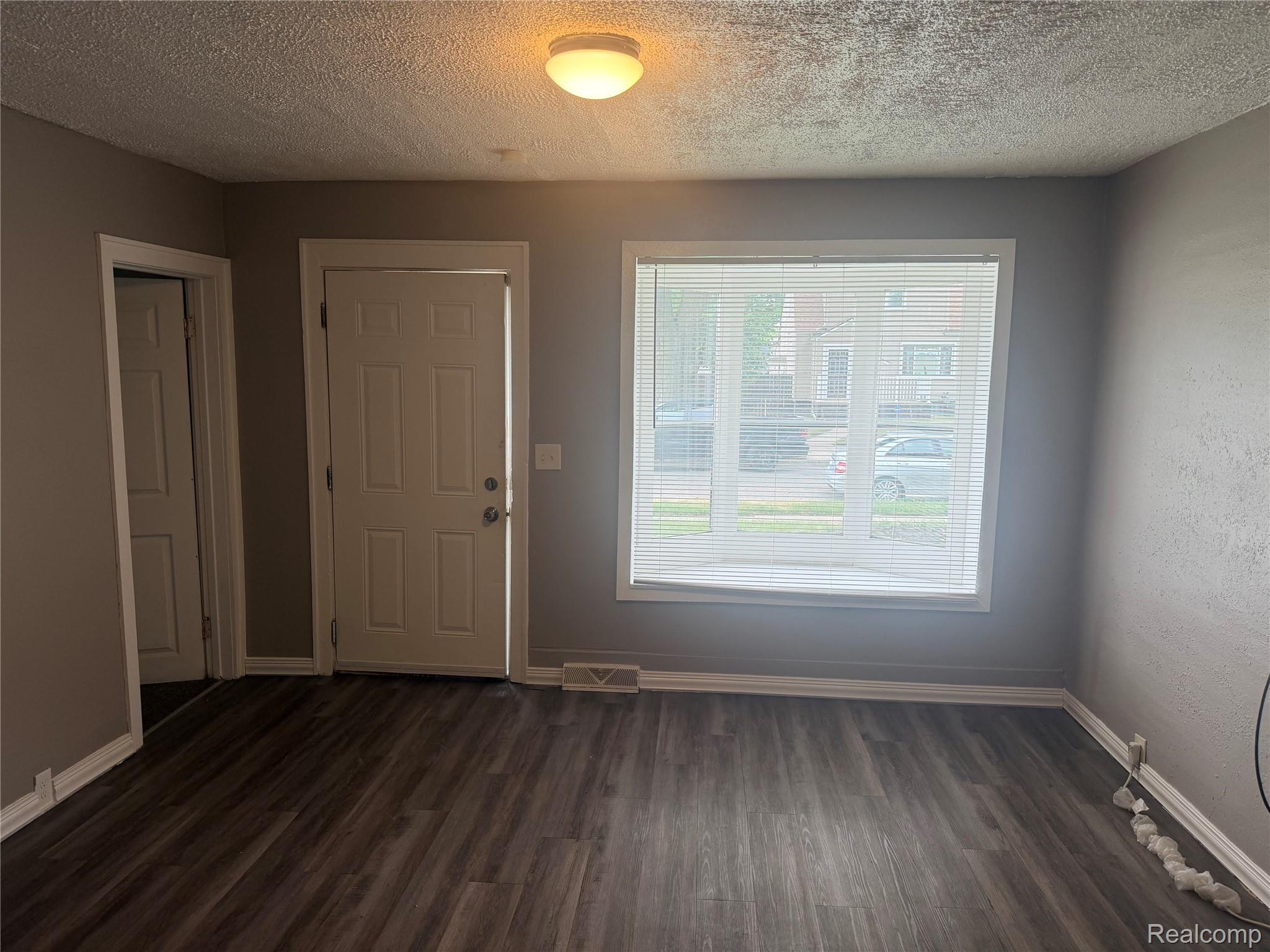 3322 Isabelle Street Inkster, MI 48141 - Photo 4 of 13 Spacious room featuring wood-finish flooring, neutral gray walls, white trim, and a prominent bay window with blinds