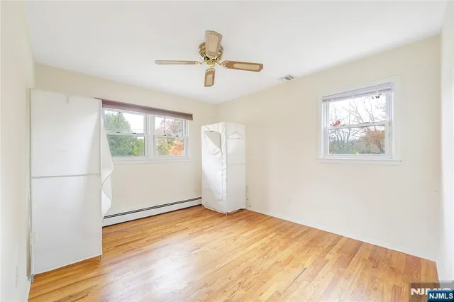 a view of empty room with wooden floor and fan