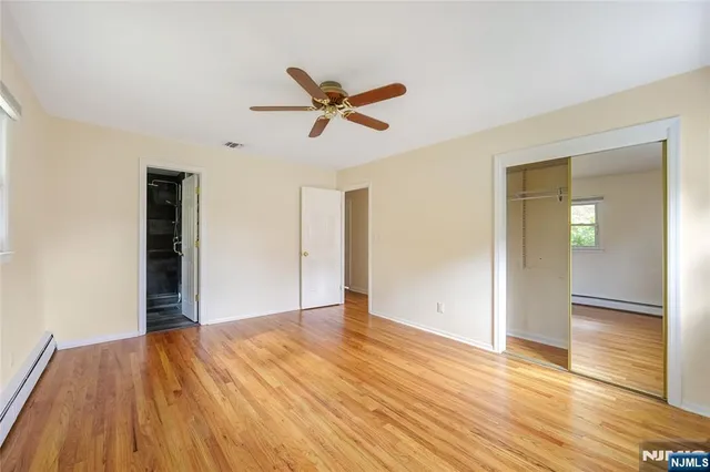 a view of empty room with wooden floor and ceiling fan