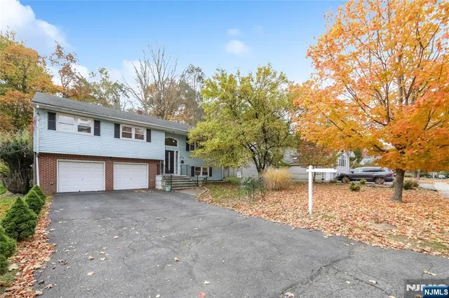 a view of a house with a yard and a large tree